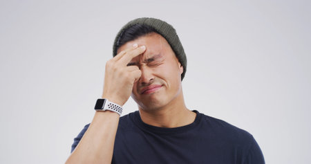 Sick, headache and man in studio with stress, brain fog and vertigo on white background with space. Migraine, tired person and pain for mental health crisis, burnout or frustrated with mistakeの写真素材