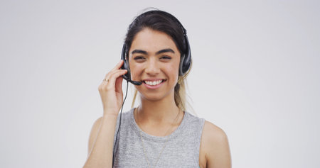 Call center, smile and portrait of woman in studio for customer support, contact us and CRM. Virtual advisor, consultant and headset with person on white background space for help desk agentの写真素材
