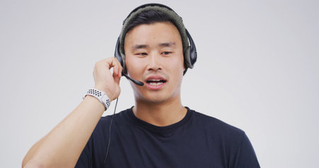 Man, talking and headset in studio for telemarketing, sales pitch and insurance advice in call center. Agent, tech and communication on white background for consultation, business contact us and CRMの写真素材