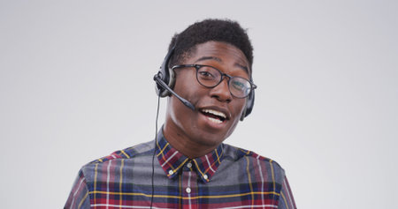 Black man, portrait and headset in studio for consultation, help or online language course at space. Tutor, glasses or tech on white background for teaching, vocabulary lesson or call center in Kenyaの写真素材