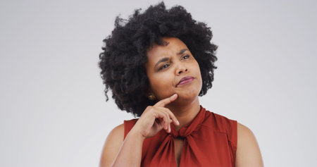 African woman, thinking and studio with doubt, mock up space and confused on white background. Person, perspective and reflection for decision, solution and choice with insight for problem solvingの写真素材