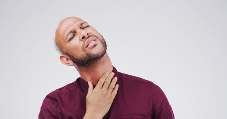Throat, hurt and man with pain on studio space for cold, sore voice and virus symptoms. Flu, choke or sick male person isolated on white background with allergy, thyroid inflammation or neck injuryの写真素材
