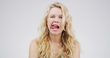 Portrait, funny face and woman with facial expression, studio or playful for comedy, humor or comic. White background, quirky and person with reaction for personality, goofy and silly with gestureの写真素材