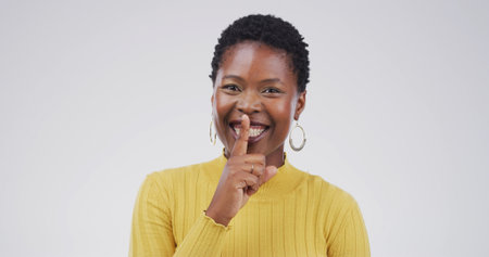 Hush, portrait and silence with black woman on studio space for gossip, secret or privacy. Emoji, finger on lips and whisper with person isolated on white background for confidential informationの写真素材
