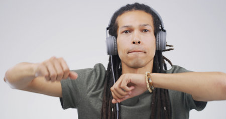 Man, portrait and dancing with headphones in studio for music playlist, streaming audio and rhythm. Space, person and technology on white background for listening to sound track, energy and movementの写真素材