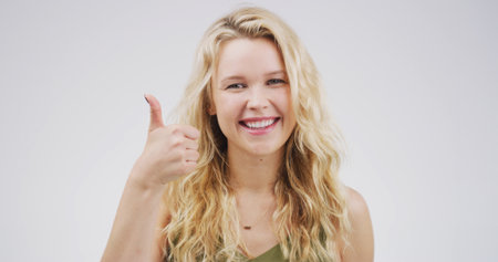 Girl, thumbs up and portrait with agreement in studio, support or motivation with success. Thank you, feedback or vote with hand gesture, review and space with approval isolated on white backgroundの写真素材