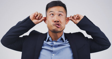 Silly man, goofy and funny face with ears in studio for monkey business on a white background. Male person, employee or model with playful attitude, comic or behaviour for joke, humor or comedyの写真素材