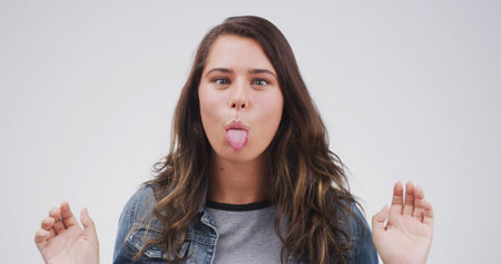 Portrait, funny face and woman in studio with tongue out on white background. Silly, goofy eyes and...