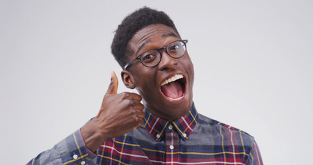 Excited, portrait or black man with thumbs up in studio for vote approval, positive feedback and yes. Mockup, happy and person with like emoji for successful review and good job on white backgroundの写真素材