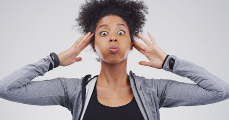 Surprise, silly and black woman in studio with funny face for, comedy and humor reaction. Facial expression, quirky and portrait of person with goofy, crazy and shocked for news on white backgroundの写真素材