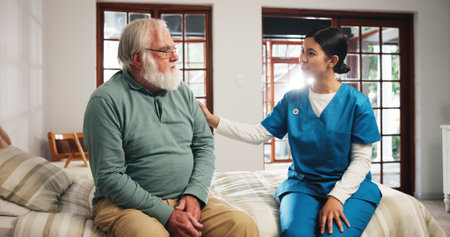 Comforting, talking and nurse with senior man in bedroom for support, help and care in nursing home. Retirement, healthcare and caregiver with old person for empathy, conversation and consultingの写真素材