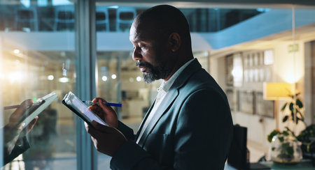 Writing, night and business black man on tablet for research notes, schedule and project management. Planning, corporate and worker on digital tech by glass for ideas, report and strategy in officeの写真素材