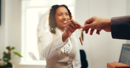 Hands, keys and welcome in hotel lobby, concierge or registration for accommodation at resort. People, check in and happy with client, hello or help desk for suite booking at hospitality lodgeの写真素材