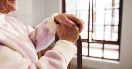 Senior woman, hands and thinking with cane for healthcare or support in retirement home. Closeup, female person or elderly patient with walking stick for mobility, balance or assisted living in houseの写真素材