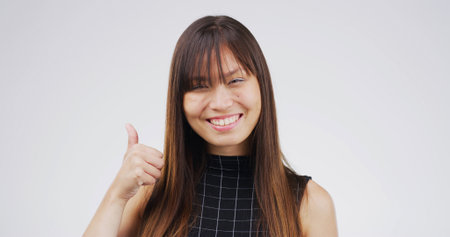 Thumbs up, smile and portrait of businesswoman in studio for agreement, feedback or vote for investment. Happy, good news and Asian financial manager with approval hand gesture by white background.の写真素材