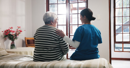 Back, talking and nurse with senior woman in bedroom for support, help and care in nursing home. Retirement, healthcare and caregiver with elderly person for empathy, conversation and consultingの写真素材