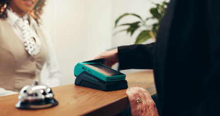 Hands, credit card and concierge with payment at hotel, service and booking with hospitality at resort. People, receptionist and support at help desk with POS fintech, transaction or machine at lodgeの写真素材