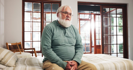 Lonely, old man and sad in bedroom, thinking or pensioner with Alzheimer and mental health in house. Depressed, elderly person and reflection in nursing home, retirement and alone with dementiaの写真素材