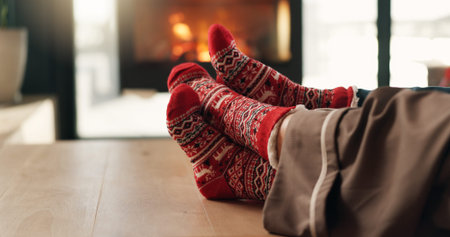 Christmas, cozy socks and feet of couple in home for vacation break, festive season and bonding. Winter, cuddle and people relax together in lounge for xmas holiday, relationship connection and loveの写真素材