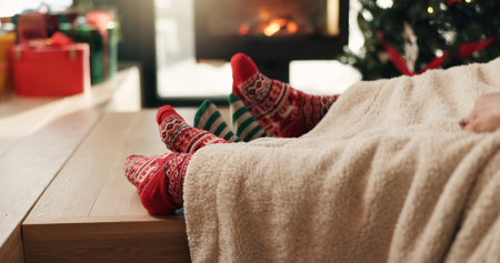 Christmas, socks and feet of family in home for vacation break, festive season or cozy bonding. Winter, cuddle and people relax together by fireplace for xmas holiday, relationship connection or loveの写真素材