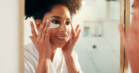 Eye mask, beauty and woman by mirror in bathroom for hydration, glow or facial routine in morning....