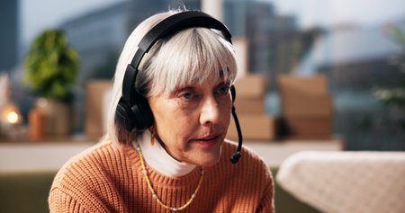 Ecommerce, headset and woman with customer service in home for delivery FAQ, verify info and help. Supply chain, mature person and microphone for package enquiry, dropshipping support and remote workの写真素材
