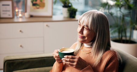 Senior woman, coffee and thinking on sofa with happy memory, daydreaming and weekend break. Smile,...