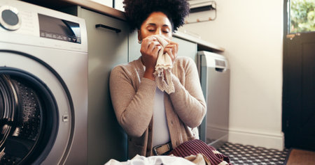 Clothes, smell and laundry with woman and washing machine for cleaning, hygiene and fabric softener. Housekeeping, cleaner and chores with person in home for aroma, fresh linen and detergent scentの写真素材