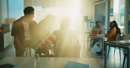 University, student and men in classroom, education and preparing for exam, talking or conversation. Lens flare, pupil and planning for test with classmate, people and friends with advice in collegeの写真素材