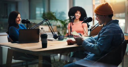 Podcast, talking and people on tablet in studio with guests for interview, discussion and conversation. Content creation, host and group with mic for recording radio show, broadcast and live streamの写真素材