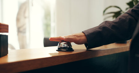Person, hands and ringing with service bell for reception or request assistance in hotel. Closeup, client or customer with alert on front desk for response, question or accommodation in luxury resortの写真素材