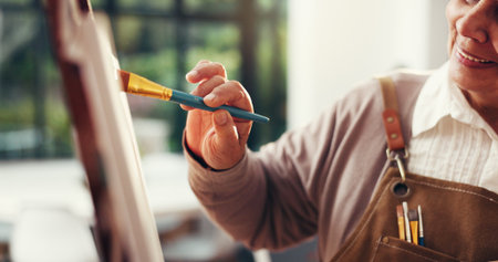Hands, painting and artwork in home with canvas, smile and process with inspiration in retirement. Elderly person, artist and brush with hobby, stroke or color for talent with creativity at houseの写真素材