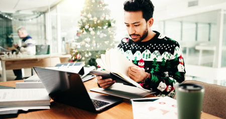 Christmas, business and man in office, notebook and deadline for annual profit audit. Xmas, person and employee with paperwork, festive and budget report with finance agency, revenue or checklistの写真素材