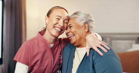 Happy, hug and nurse with senior woman in home for support, empathy or compassion on good news. Smile, relax and caregiver embracing elderly female person in bedroom for healthcare checkup in house.の写真素材