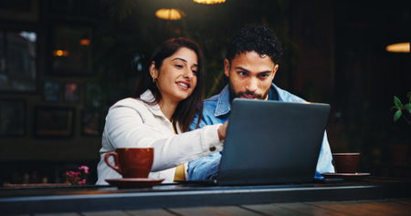 Laptop, conversation and couple with coffee in cafe with connection, bonding or talk on morning date. Happy, cappuccino and man with woman on computer for social media, research or blog in restaurantの写真素材