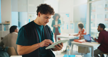 Tablet, learning and man in university classroom for study, development or research project online. Technology, student or person in college for knowledge, reading thesis or scholarship for educationの写真素材