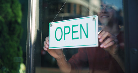 Happy person, hands and window with open sign in cafe for startup or ready for business. Storefront, signage or owner with poster, welcome or message for hospitality, advertising or service in shopの写真素材