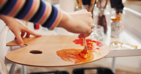 Hands, paintbrush and palette with person in studio apartment for creative expression or illustration. Art, mixing acrylic and painting with talented artist in home for hobby, practice or skillの写真素材
