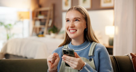 Phone, fist pump and woman on sofa in home with winning, bonus or prize for online gambling. Happy, technology and female person on cellphone with celebration for lottery announcement in house.の写真素材