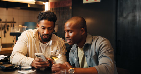 Alcohol, friends and men with phone in restaurant for social media, online message and conversation. Nightclub, talking and people with wine, drinks and smartphone for reunion, hangout and weekendの写真素材