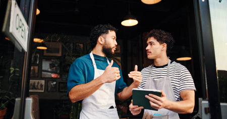 Tablet, conversation and people in cafe, employees and hospitality with help, menu items or teaching. Business, cooperation or men in restaurant, tech or digital app for online order, support or talkの写真素材