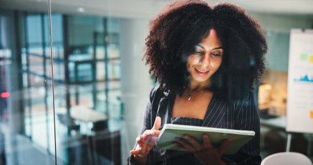 Reading, business woman and tablet in office for investment report or trading. Technology, research and happy African worker with email for financial update, stock market and review project onlineの写真素材