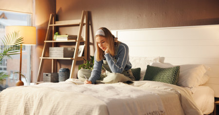 Girl, student and writing in notebook on bed for academic planning, study calendar or test reminder. Personal diary, person and taking notes in home for assignment schedule and weekend productivityの写真素材
