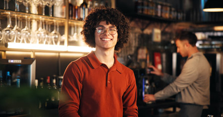 Bartender, man or smile at counter in pub for friendly welcome, customer service or hospitality. Small business, manager and confidence at restaurant with portrait, ready for happy hour or managementの写真素材