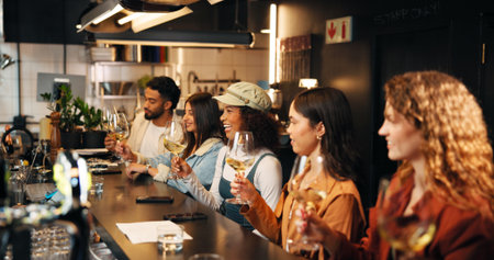 Friends, happy and people with wine tasting at pub for experience, social gathering or bonding. Group hangout, night and swirling alcohol at restaurant to release aroma, test quality or weekend breakの写真素材