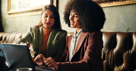 Business, people and reading on laptop at cafe for planning, research and feedback on article. Women, talk and PC for creative ideas, review schedule and teamwork for story information at coffee shopの写真素材