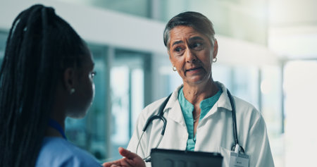 Collaboration, medical or tablet with doctor and nurse in hospital for internship or learning. App, healthcare and teaching with student and mature woman mentor in clinic for development or trainingの写真素材