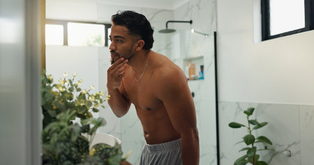 Bathroom, grooming and man with beard, house and inspection of fresh shave, self care and shirtless. Checking, reflection and maintenance of facial hair in home, person and getting ready with mirrorの写真素材