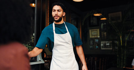 Entrance, coffee shop and waiter with customer for welcome, greeting or hospitality service. Industry, entrepreneur and male small business owner with consumer at doorway of restaurant or cafe.の写真素材