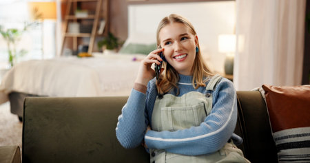 Happy woman, talking or listening with phone call on sofa for communication or conversation in home. Female person, user and chatting with smile on mobile smartphone for friendly discussion in houseの写真素材